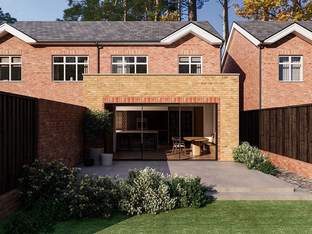 A modern two-storey house with a beige brick exterior and a back extension, featuring large sliding glass doors opening to a patio and garden. The house has a neatly landscaped backyard with green shrubs and a wooden fence on both sides.