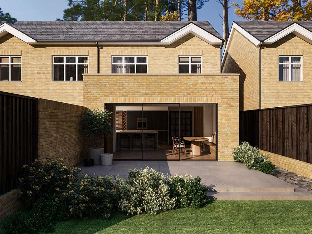 A modern two-storey house with a yellow brick exterior and a back extension, featuring large sliding glass doors opening to a patio and garden. The house has a neatly landscaped backyard with green shrubs and a wooden fence on both sides.