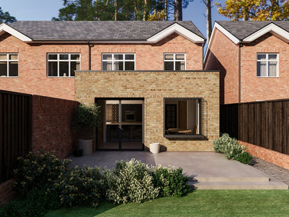 A modern two-storey house with an extended single-storey section in the back garden. The house features large windows, a French-style folding door, and an extruded box window. The extension is yellow brick, while the rest of the house is red brick. The back garden has a paved patio, steps down to a lawn, bushes, and a wooden fence. Similar houses and trees are visible in the background.